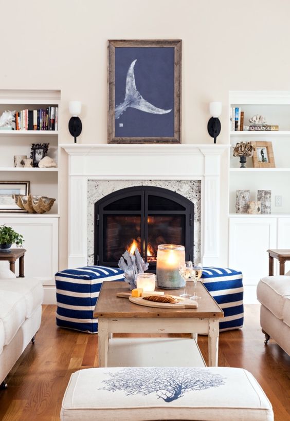 a modern coastal living room with white furniture, striped ottomans, decorative seashells and corals plus an artwork