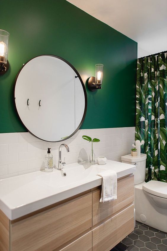 a modern tropical bathroom with a green wall and white subway tiles, a tropical curtain and a floating wooden vanity