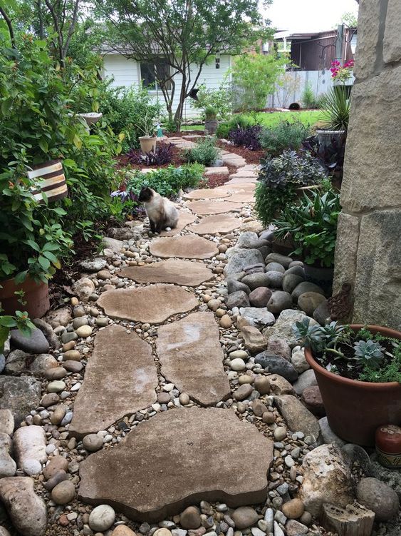 a natural and rustic garden path of larger stones and smaller pebbles around looks cool and chic