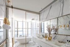 a refined white marble bathroom with a glazed wall, a tub, a mirror and pendant lamps and a floating vanity