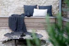 a relaxed outdoor space with a built-in corner bench with pillows, a wrought iron fire bowl on a brick spot is a lovely nook