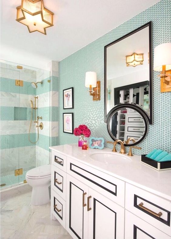 a sea-inspired bathroom with aqua tiles, a catchy black and white vanity and gold fixtures