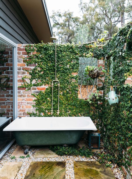 a shabby chic bathroom with brick walls done with climbing greenery and a green bathtub