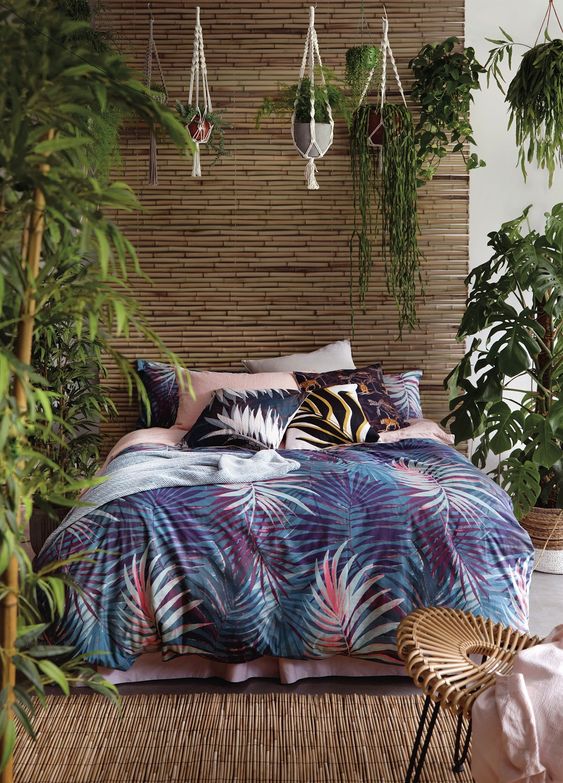 a single bamboo wall, a bamboo rug, lots of potted greenery and bright tropical bedding create an ambience