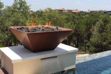 a square aged metal fire bowl place right on the fountain allows you to enjoy two elements in one and makes your backyard spectacular