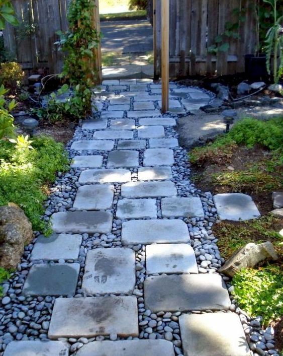 a stylish and comfrotable garden path of pebbles and simple stones contrasts the greenery around