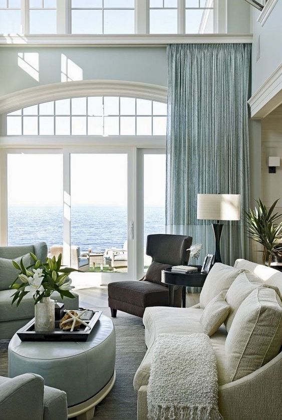 a stylish beahc living room with an aqua curtain, aqua furniture, a dark chair and a creamy sofa
