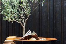 a stylish modern fire bowl with a copper bowl and black legs plus a firewood stack next to it is a cool idea for outdoors