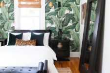 a stylish tropical bedroom with a wicker shade, a tropical print statement wall and black furniture for a contrast