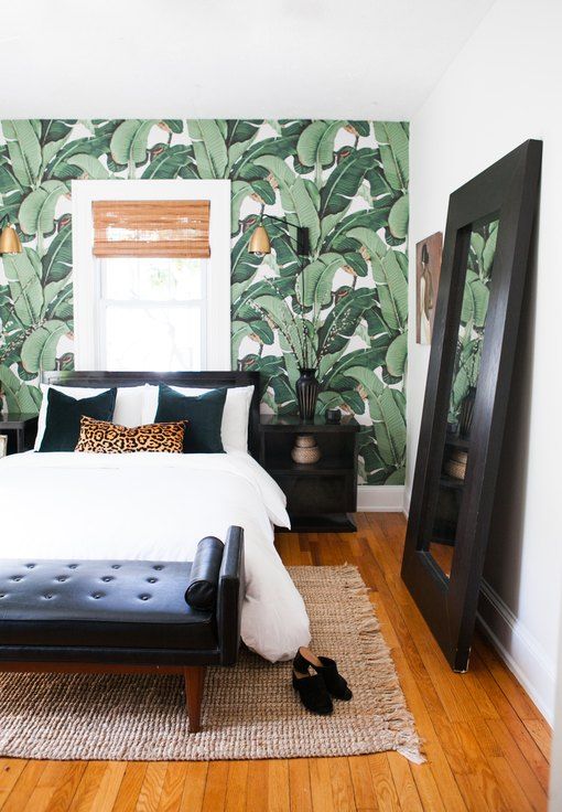 a stylish tropical bedroom with a wicker shade, a tropical print statement wall and black furniture for a contrast