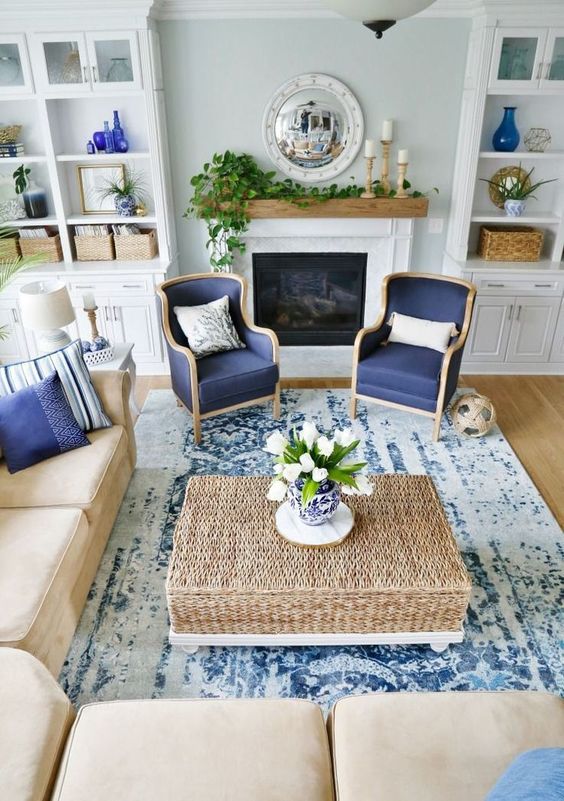 a traditional coastal living room with a tan and navy color scheme, rattan, leather and a mantel with greenery
