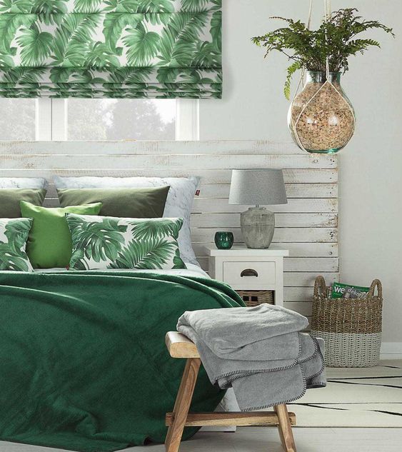 a tropical Roman shade and bedding, a basket and a potted plant brign a tropical feel to this neutral sleeping space