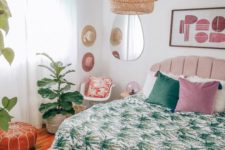 a tropical bedroom with tropical bedding, a wicker pendant lamp, potted plants and an abstract artwork
