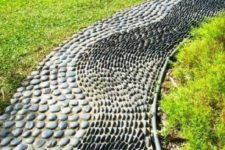a unique garden path with grey pebbles placed vertically and horizontally creating a pattern