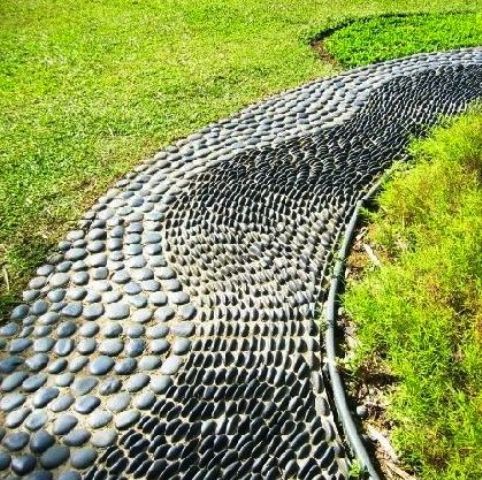 a unique garden path with grey pebbles placed vertically and horizontally creating a pattern
