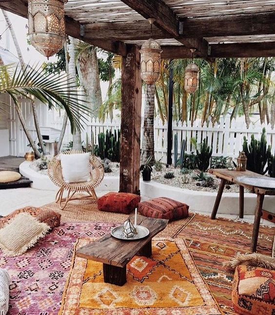 a welcoming Moroccan patio wiith wicker and wooden furniture, Moroccan lanterns and colorful rugs and cushions