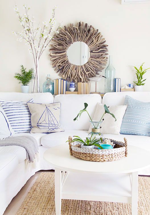 a welcoming beach living room with a white sofa, a basket for accessories and a driftwood mirror
