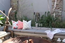 a welcoming outdoor space with a corner bench, a large wrought metal fire bowl, some greenery and whimsical decor