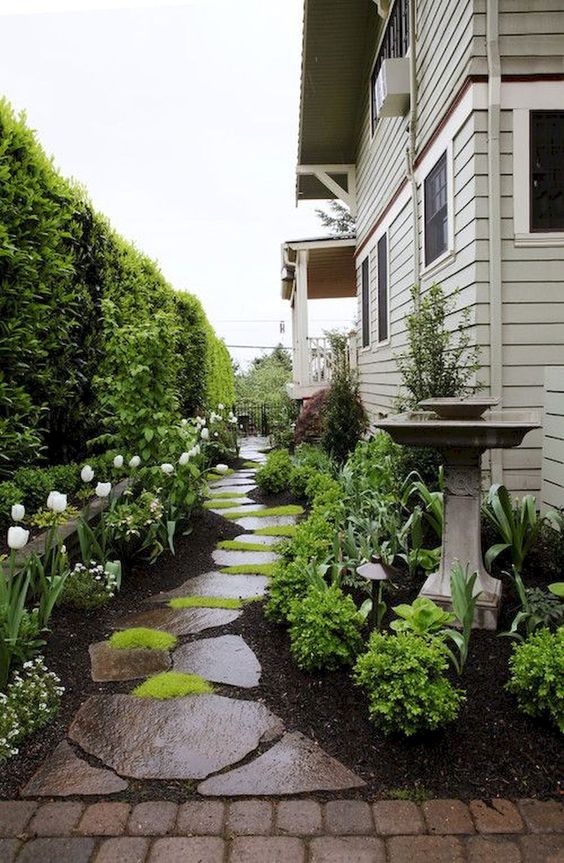 a zen stone garden path with dark rough pieces and bright moss growing in between