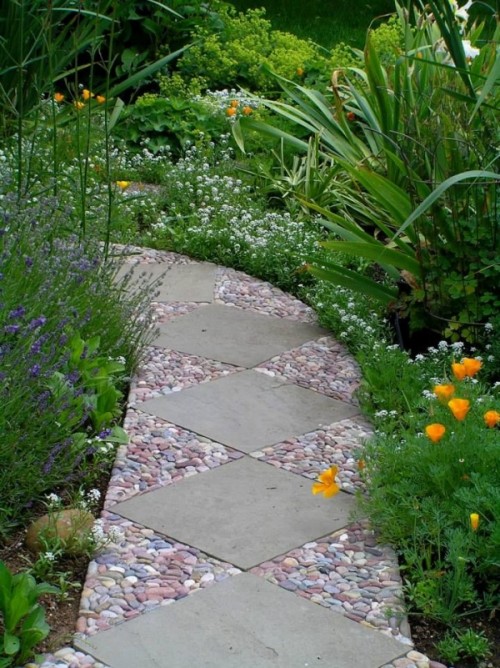 an eye-catchy garden path done with large grey tiles and red, blue and white pebbles around them