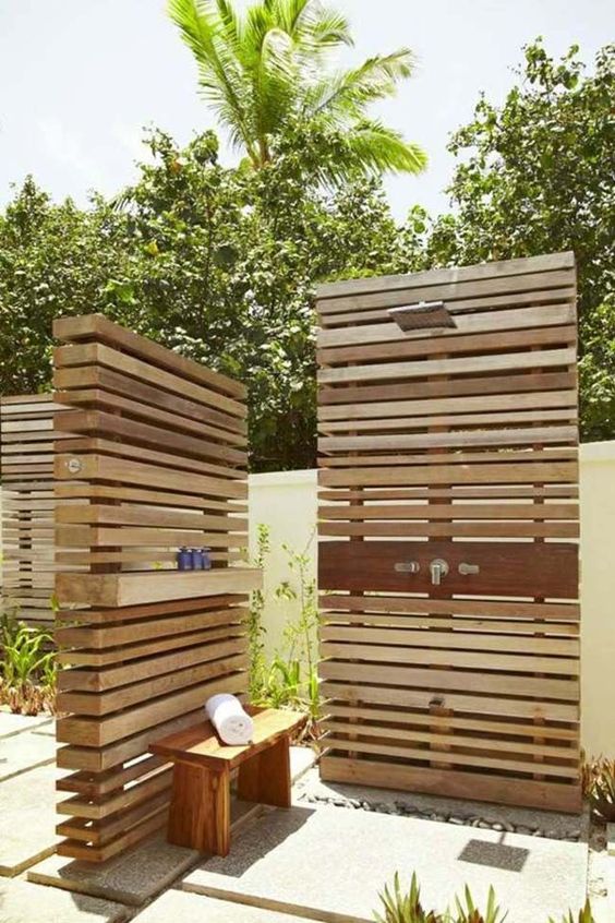 an outdoor shower with plank screens and tiles on the ground plus a bench for comfort