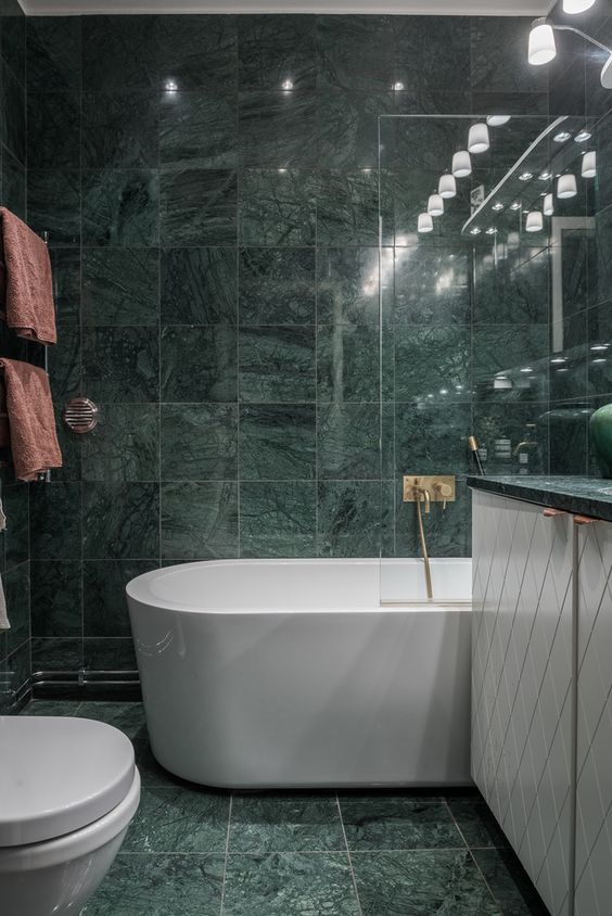 green marble tiles covering the whole bathroom make it a refined and a bit moody space