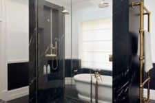 pure elegance and drama in this bathroom done with black marble, blakc penny tiles and a white vintage tub