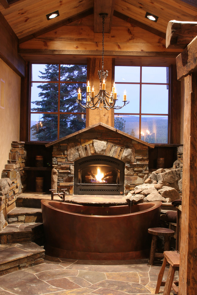 a gorgeous chalet bathroom with much natural stone and wood, with a large metal tub  (High Camp Home)