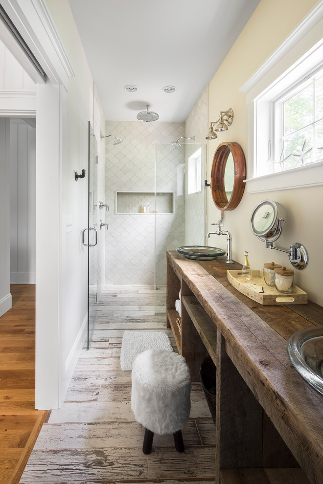 a cozy rustic meets contemporary bathroom with a large vanity, a whitewashed wooden floor and a round mirror (GMT Home Designs Inc.)