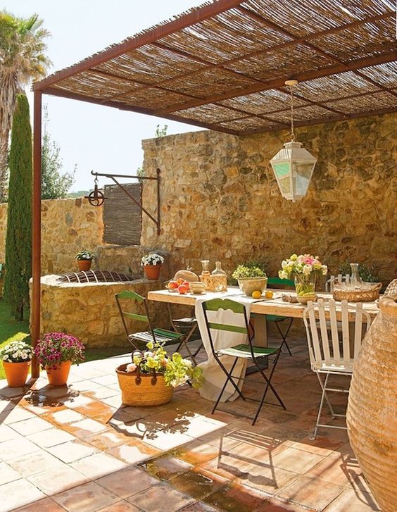 a French famrhouse patio with a mosaic glass lamp, mismatching chairs and potted greenery