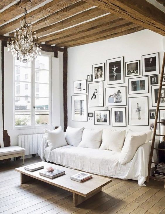 a French rustic space with a wooden beam ceiling, a wooden table and a wooden floor plus a crystal chandelier for a chic touch