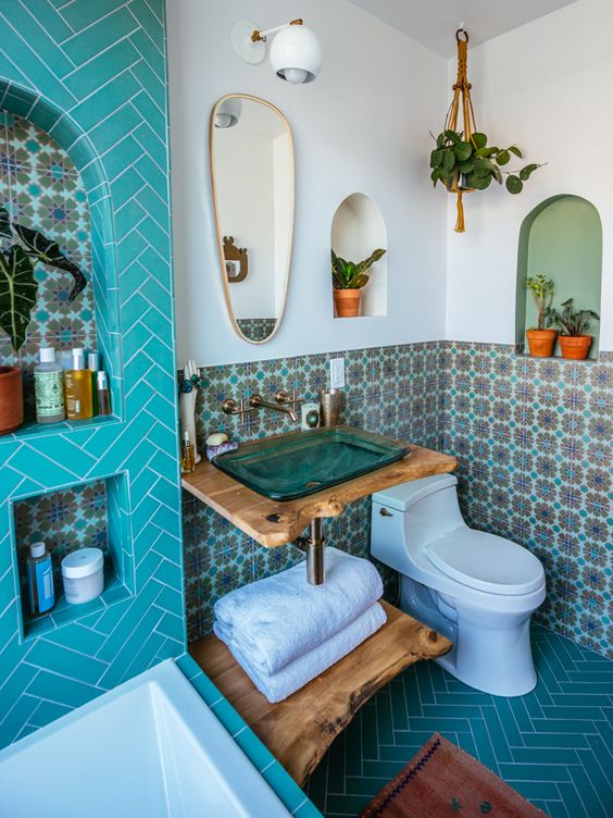 a Moroccan-inspired bathrooms with colorful tiles, niches for storage, potted greenery and a turquoise glass sink