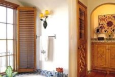 a bathroom with a Moroccan rug and blue and white tiles and shutters on the window