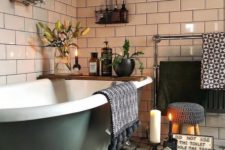 a boho bathroom done with pretty Moroccan tiles, potted plants and blooms, candles and a green clawfoot tub