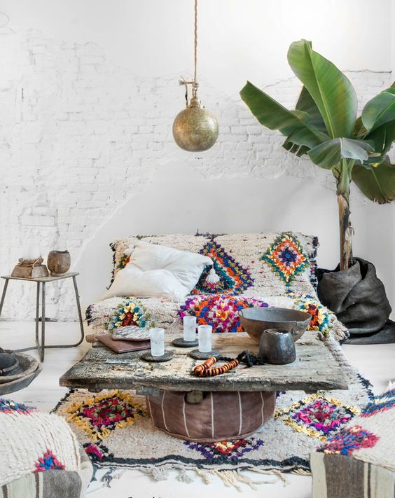 a boho living room with touches of color and pattern, with a leather ottoman and cushions