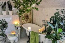 a boho oasis with lots of potted greenery, candles, lights and a clawfoot bathtub plus baskets