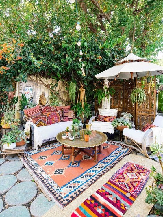 a bright boho patio with rattan and wicker furniture, printed rugs and pillows, lanterns and hanging planters