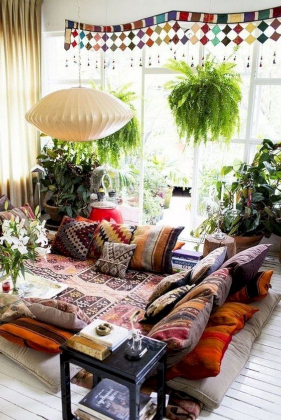 a bright sunken living room with colorful and patterned textiles and lots of potted greenery