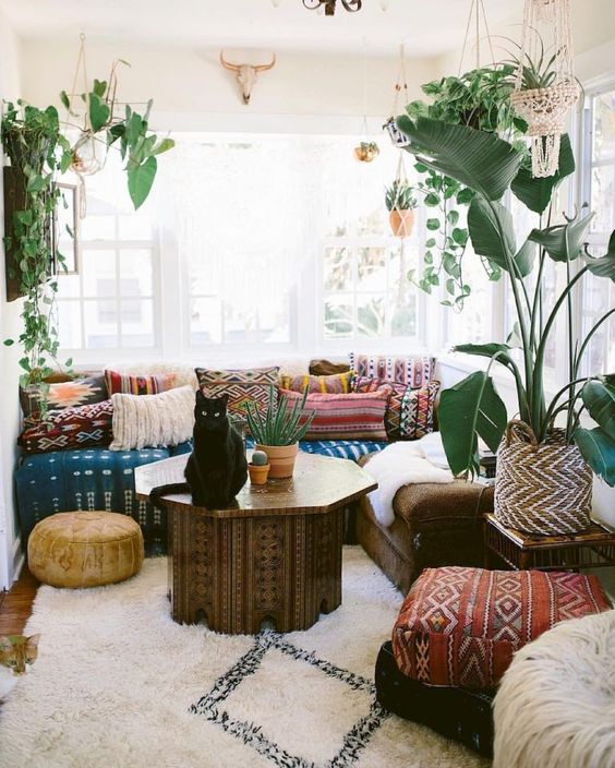 a chic Moroccan living room with bright patterned textiles, a painted coffee table and potted greenery