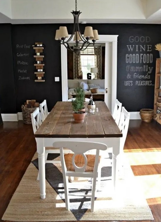 a chic farmhouse dining space with a rustic wooden dining set, a chalkboard wall and a vintage chandelier