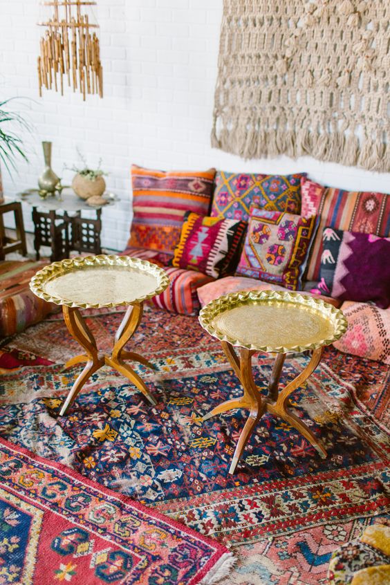 a colorful living room with bright textiles and patterns, gold tables and a macrame hanging