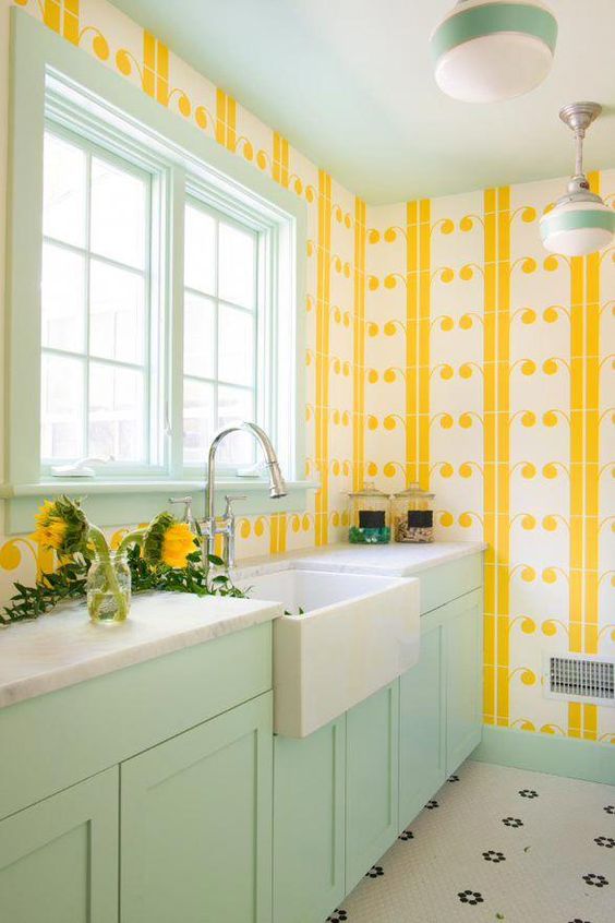 a colorful welcoming kitchen with yellow print wallpaper walls, a mint frame window and mint cabinets for a bold look