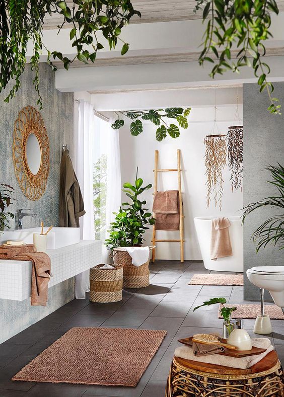 a contemporary meets boho space with potted greenery, baskets, rattan furniture, a wicker mirror and a ladder