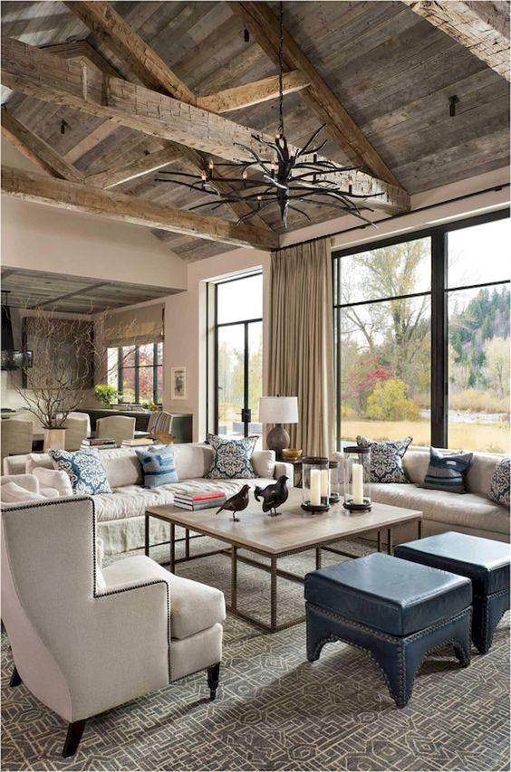 a contemporary rustic living room with a reclaimed wood ceiling with beams, wooden tables, leather stools and neutral furniture