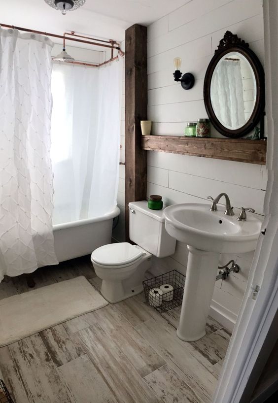 a farmhouse bathroom with whitewashed wood plank walls and a floor,, copper touches and vintage items