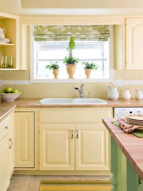 a farmhouse kitchen with light yellow cabinets and a beadboard backsplash, a green kitchen island and a green printed curtain