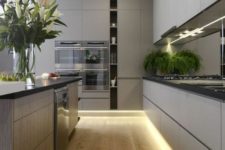a grey minimalist kitchen with sleke cabinets, black countertops, built-in lights and pendant lamps