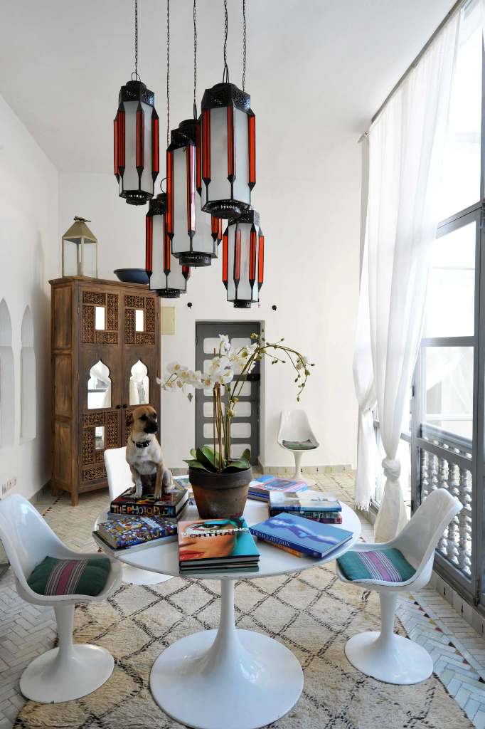 a lovely Moroccan dining space with modern white furniture, bright Moroccan-inspired pendant lamps and a carved wooden wardrobe