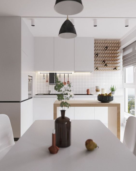 a minimalist white kitchen with built-in lights, a wine bottle rack, a minimal wooden kitchen island and a white dining set