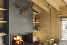 a modern rustic living room with wooden walls and a ceiling, a fireplace, firewood stored by it and antlers